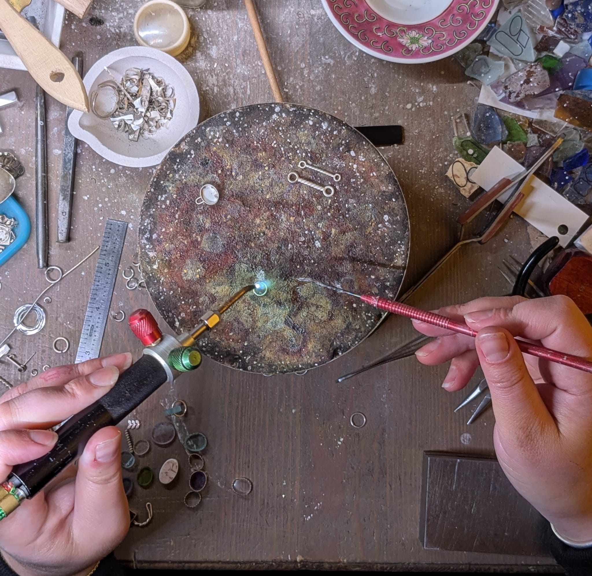 The artist's hands working on a jewelry piece.